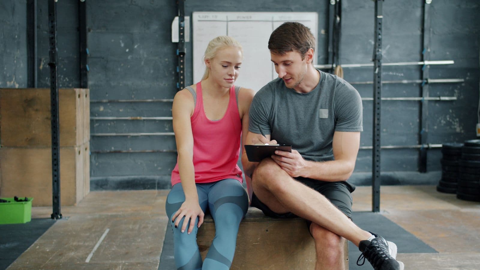 A personal trainer going through a workout plan with a client in a gym